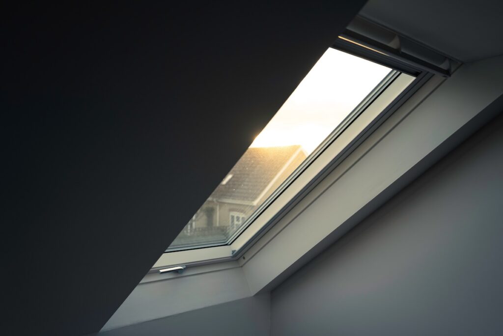 Newly installed, high insulated skylight window seen within the first floor of a house extension. Looking out to a neighbour's house at dusk.