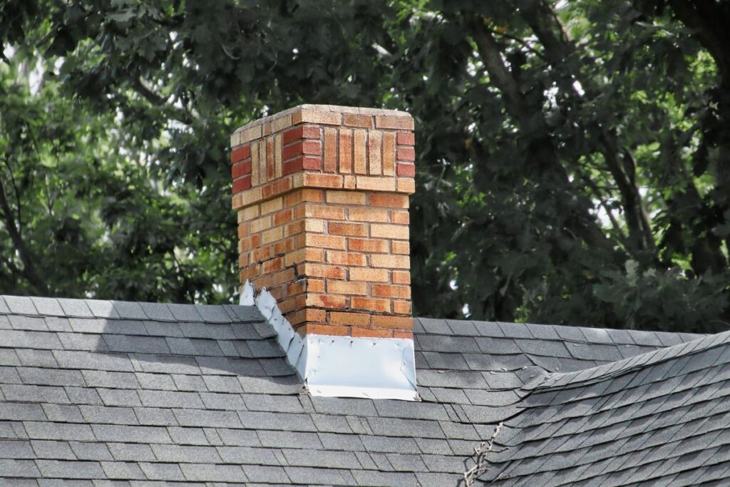 chimney flashing charcoal shingles roof orange brick wall