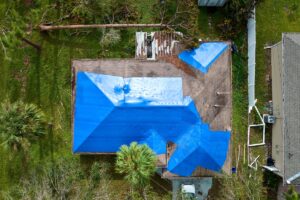storm damage roof insurance blue tarp on roof after hail