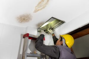 signs of roof leak in attic man inspecting entrance water stains on ceiling